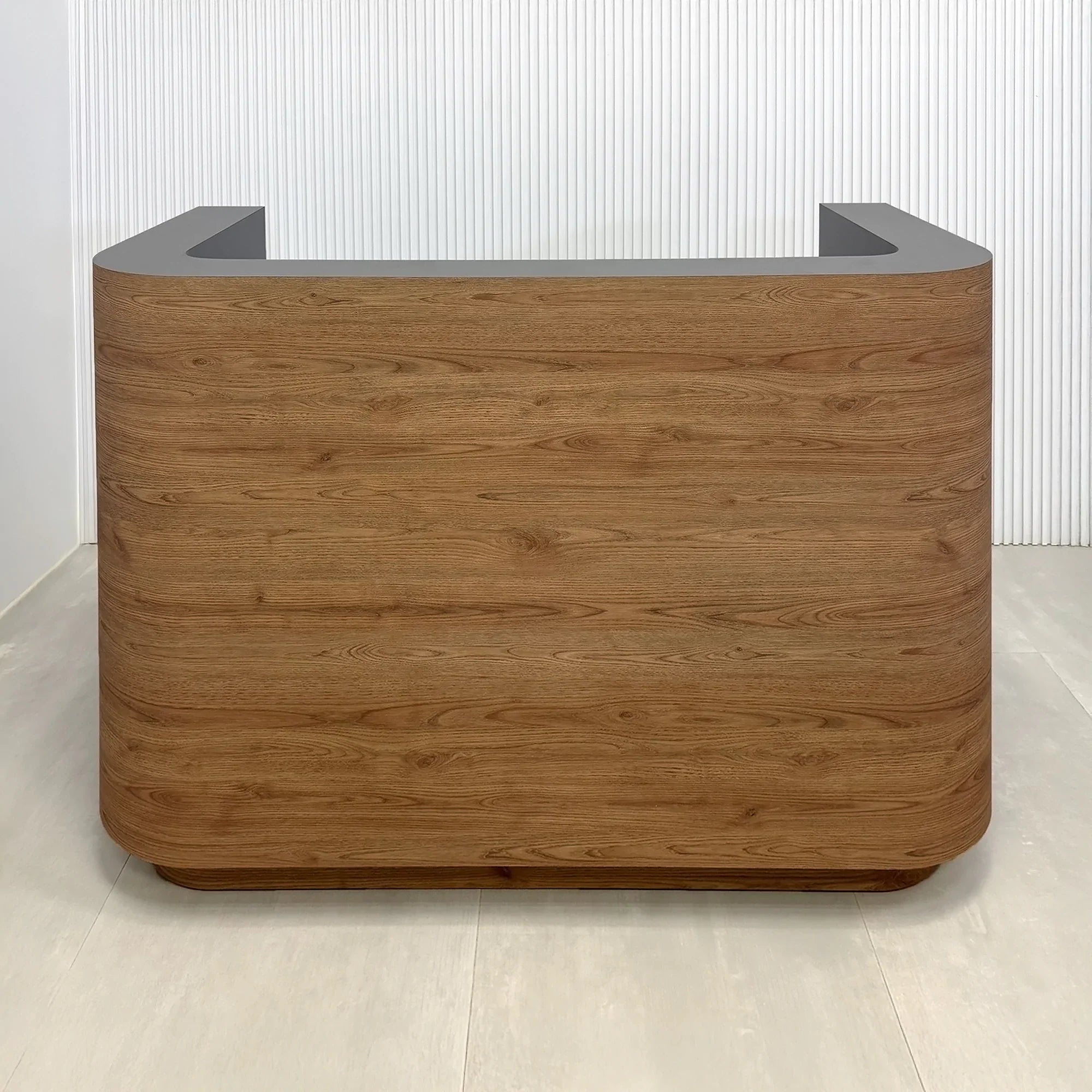 60-inch Nola Custom Reception Desk with Spiced Chestnut 1517 matte laminate front and Toe-Kick. Storm Gray matte laminate workspace and White LED. 