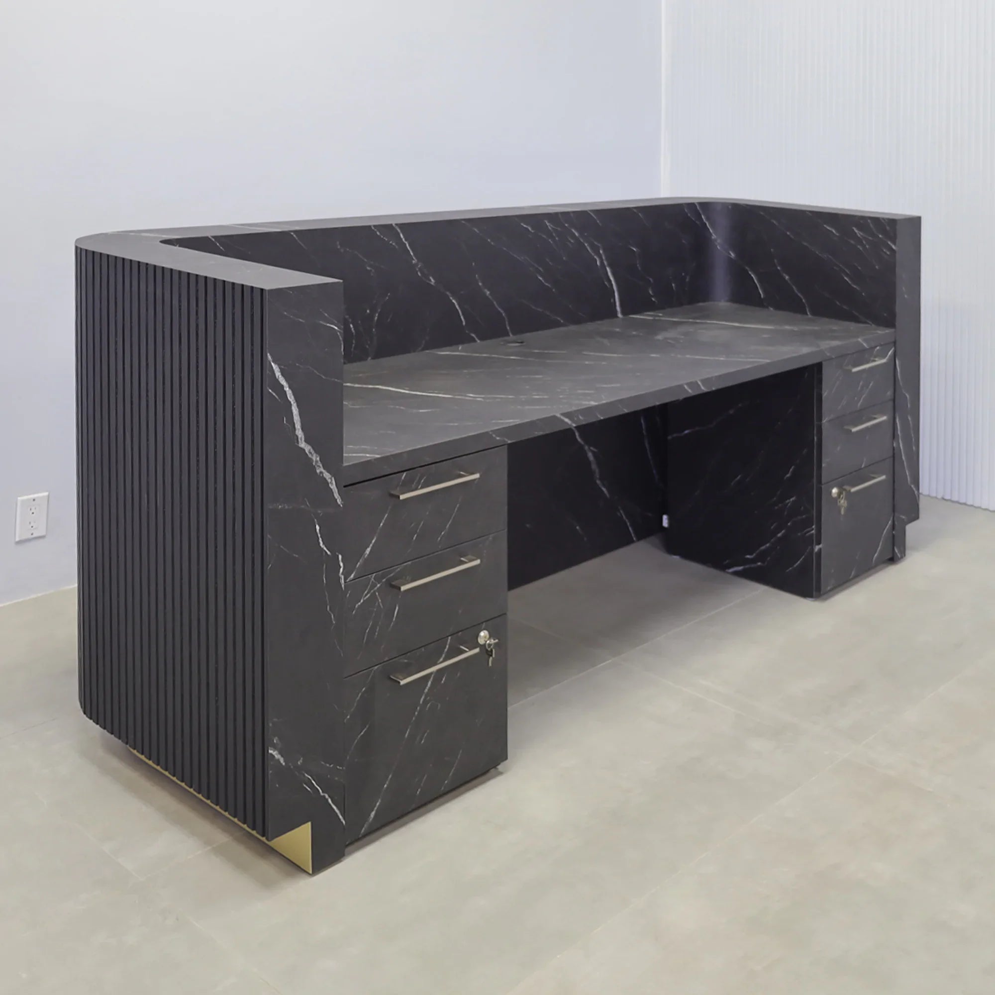 90-inch Nola Custom Reception Desk with Black Traceless Tambour main desk, and Black Stone PVC laminate workspace. Gold aluminum toe-kick, and warm white LED. 